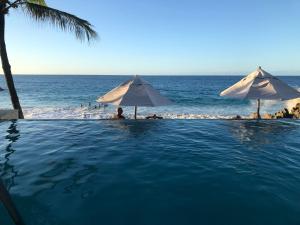 苏莎亚Vacations in the Caribbean Paradise的毗邻大海的带遮阳伞的游泳池