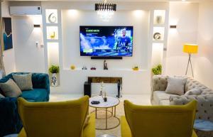 阿布贾Morak Homes - Luxury 4 bed home with PS5, 24hrs electricity, Super fast Wifi, Snooker, Games room - in a secured estate的客厅配有两把椅子和墙上的电视