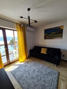 克鲁斯兹考采Apartament Lake View z sauną i widokiem na jezioro的客厅配有黑色沙发和黄色窗帘