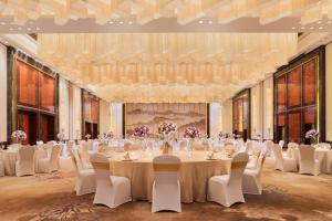 南昌南昌万达嘉华酒店的一个带长桌子和椅子的大型宴会厅
