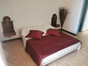 圣安娜Chez Chrys的卧室内的一张带两个红色枕头的床