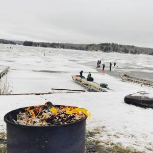 HarcourtBaptiste Lake Lodge的冰冻湖上的火坑,冰上的人