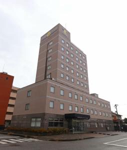 高冈市Smile Hotel Takaoka Ekimae的一条高大的棕色建筑,坐在街道边