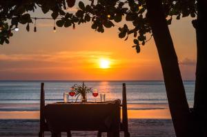 高兰Klongdao Sunset Villa的海滩上的桌子,背面是日落