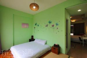 三义三义竺梦园民宿的绿色卧室配有一张床,墙上挂着鲜花