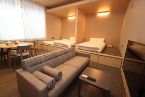 福冈White Crystal RoomA的客房设有两张床、一张沙发和一张桌子。