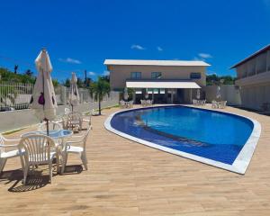 拉巴拉德纳圣安东尼奥Paraiso Barra Hotel的游泳池配有椅子和一张桌子及遮阳伞