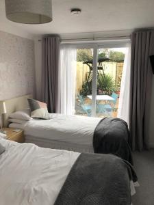 贝辛斯托克Basingstoke En Suite Room in Garden Annex的一间卧室设有两张床和一个带庭院的窗户。