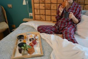 奇尼塞洛巴尔萨莫La Cordata Accommodation - Hotel Woodhouse的坐在床上的女人,带上一盘食物