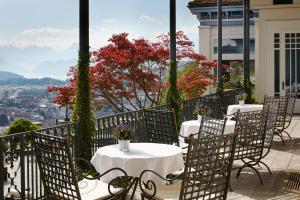 卢塞恩古奇城堡酒店的阳台上摆放着一排桌椅,可欣赏到风景