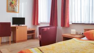 诺德奈Pension Haus Weierts的酒店客房配有一张床和一张书桌及一台电视