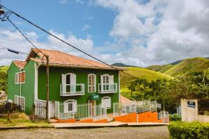 康赛瓦托利亚Pousada Conservatória的一座绿色的白色房子,后面有一座小山