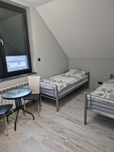 库特诺Noclegi 24/h Leszczynek的一间设有两张床和一张桌子及椅子的房间