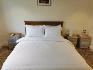多基Coliemore Acommodation Dalkey的一间卧室配有一张带2个床头柜的大型白色床