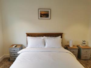 多基Coliemore Acommodation Dalkey的一间卧室配有白色床和2个床头柜