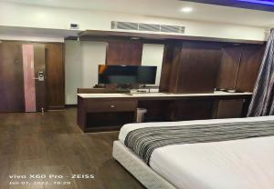 钦奈Hotel M Grand的配有一张床和一台平面电视的酒店客房