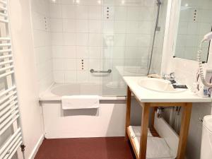 IsberguesHôtel - Restaurant "Histoire de Bistrot"的白色的浴室设有水槽和浴缸。