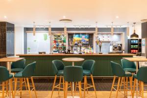 南安普敦假日南安普敦伊斯特利酒店的餐厅内的酒吧配有绿色的桌椅
