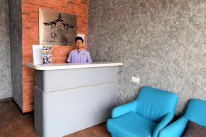 瓜拉丁加奴DJ CITI INN HOTEL的站在柜台后面,拿着两把蓝色椅子