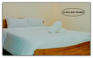 CanaguinimJJ Holiday Homes的一张带白色床单的床和一个读好莱坞房屋的标志