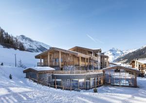 兰斯勒维拉德Les Balcons Platinium Val Cenis的一座大木结构建筑,在积雪中,与群山交织