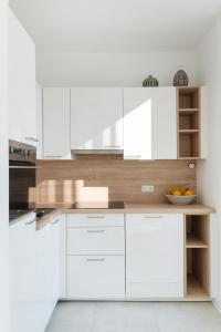 维也纳Sophienne Apartments的白色的厨房,配有白色的橱柜和一碗水果
