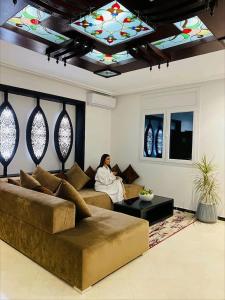 纳祖尔Aparthotel & Hotel Doha的坐在带天花板的客厅沙发上的女人