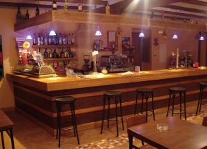 CerolleraHostal La Cerollera的餐厅里的酒吧,有桌子和凳子
