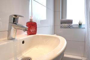 鲁尔河畔米尔海姆Schicke & helle Wohnung in Mülheim an der Ruhr的浴室水槽和红色肥皂瓶