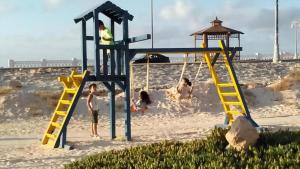 马特鲁港شاليهات بورتو مطروح فيو بحر Porto Matrouh Sea View Families Only的一群儿童在海滩上的游乐场玩耍