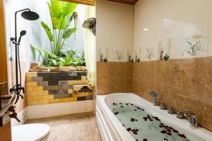 潘切Sea Night Hotel的带浴缸、卫生间和植物的浴室