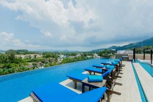 普吉镇Aristo 1 Phuket的游泳池上一排蓝色的躺椅