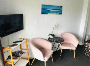 芒格努伊山蓝色天堂汽车旅馆 的两张粉红色的椅子、一张桌子和一台电视机