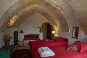 乌奇希萨尔卡帕多切城堡酒店的客厅设有两张红色的床和拱门