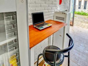 巴图Super OYO 90828 Ara Guest House的一张笔记本电脑,坐在木柜台上,椅子