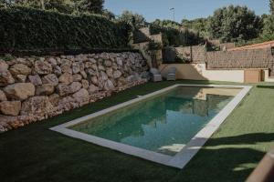 科尔百托Collbato Resort.的一座游泳池,位于石墙旁的庭院内
