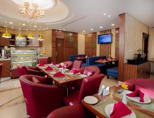 吉达太阳公园套房酒店的餐厅设有红色的桌椅和电视