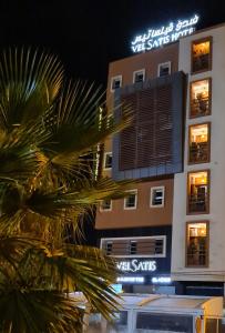 贝尼迈拉勒Hotel VELSATIS的前面有棕榈树的建筑