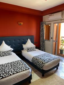 贝尼迈拉勒Hotel VELSATIS的红色墙壁客房的两张床