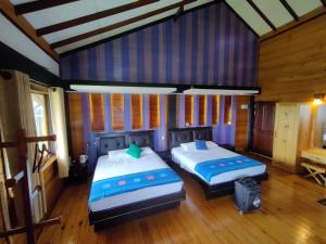 努沃勒埃利耶Amansara Bungalow的配有木墙和木地板的客房中的两张床