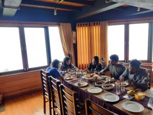 努沃勒埃利耶Amansara Bungalow的一群坐在餐桌上吃食物的人
