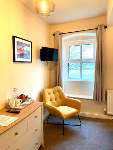 斯基普顿The Green at Burnsall的一张黄色椅子,位于带桌子和窗户的房间