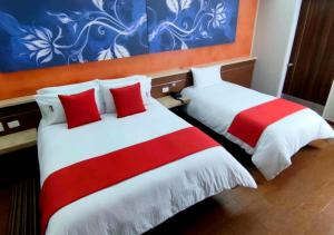 加拉加斯Novo Hotel的两张位于酒店客房的床,配有红色和白色床单