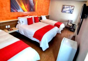 加拉加斯Novo Hotel的酒店客房带两张红色和白色的床单