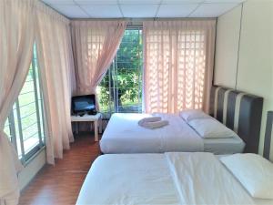 Kampong Bukit LintangHasina Resort @Sedili的配有窗户的酒店客房内的两张床