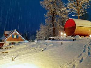 普热谢卡Kolorowe Karkonosze的一座有积雪覆盖的院子,里面有一座建筑和一桶桶