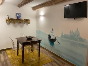 威尼斯CA' DE' KOCAI的配有电视和桌子的房间,墙上有一条船