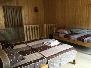 K'veda BzubzuCottages in mountains的带木墙的客房内的三张床