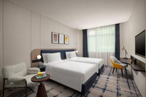武汉武汉新华voco酒店的一间酒店客房,配有白色的床和电视