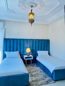 纳祖尔Aparthotel & Hotel Doha的一间卧室配有两张床和一张带台灯的桌子